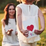 The child's daughter congratulates her mother and gives her a postcard. Mother and girl smile and hug